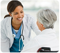 Doctor leans down to smile at elderly patient facing away from camera